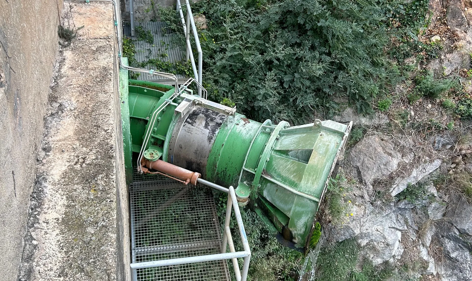Turbina hidràulica pintada de verd sobre estructura de formigó